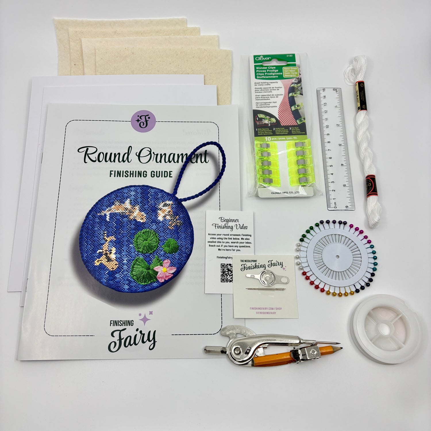 Beginner Finishing Kit contents laid out including matboard, batting, wonderclips, cording, lacing thread, and project bag for finishing needlepoint round ornaments