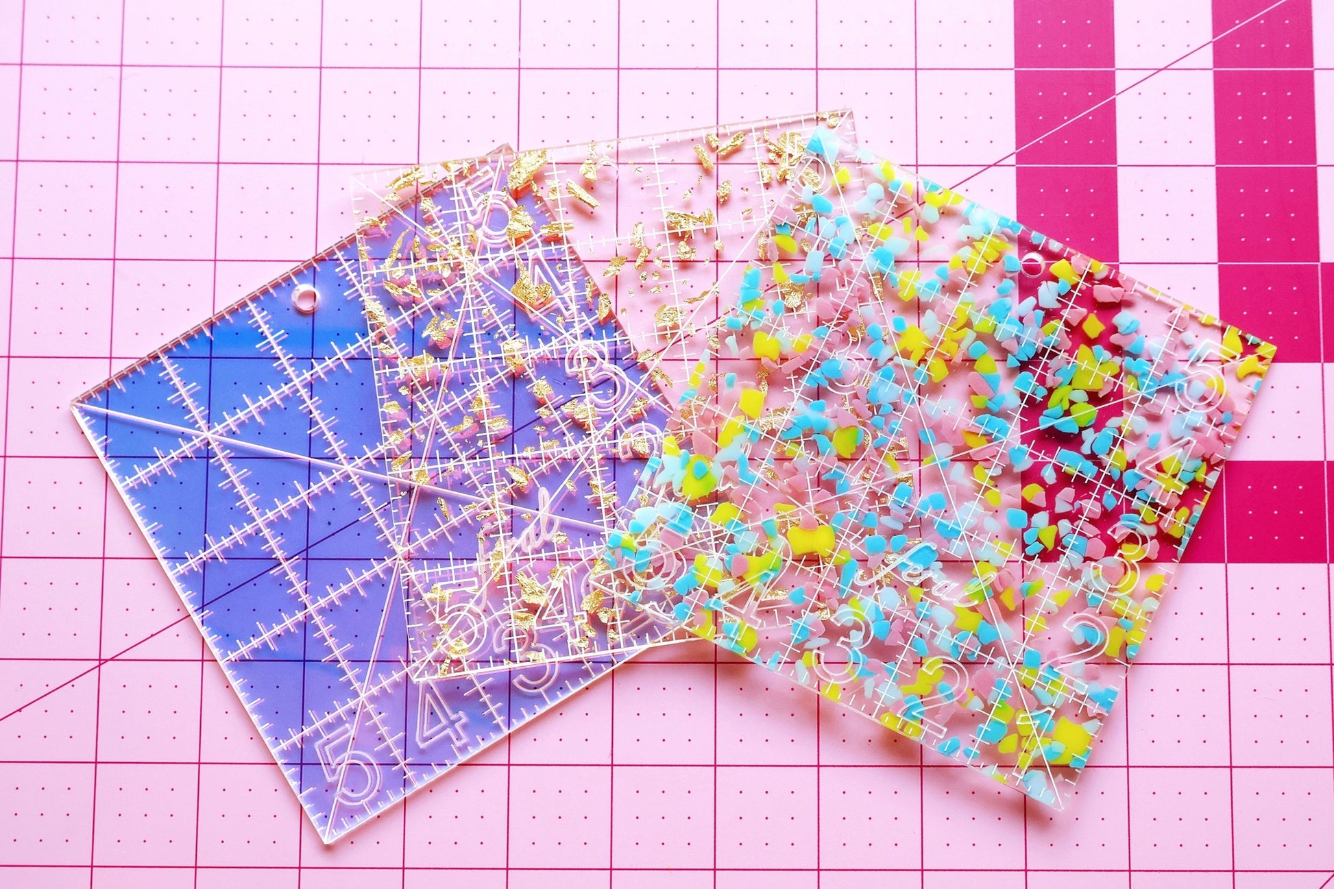 Feral Notions 5 inch square rulers shown in all three colorways, Golden, Confetti, and Iridescent, curated by the Needlepoint Finishing Fairy for needlepoint finishing