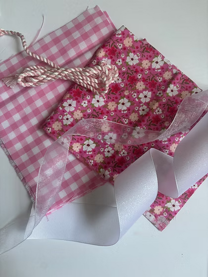 Stitch It Angel Add On Kit contents including organza ribbon, grosgrain ribbon, cording, and gingham fabric for needlepoint angel ornament finishing. Pink color variation. 