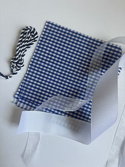 Stitch It Angel Add On Kit contents including organza ribbon, grosgrain ribbon, cording, and gingham fabric for needlepoint angel ornament finishing. Blue color variation.