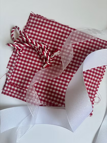 Stitch It Angel Add On Kit contents including organza ribbon, grosgrain ribbon, cording, and gingham fabric for needlepoint angel ornament finishing. Red color variation.